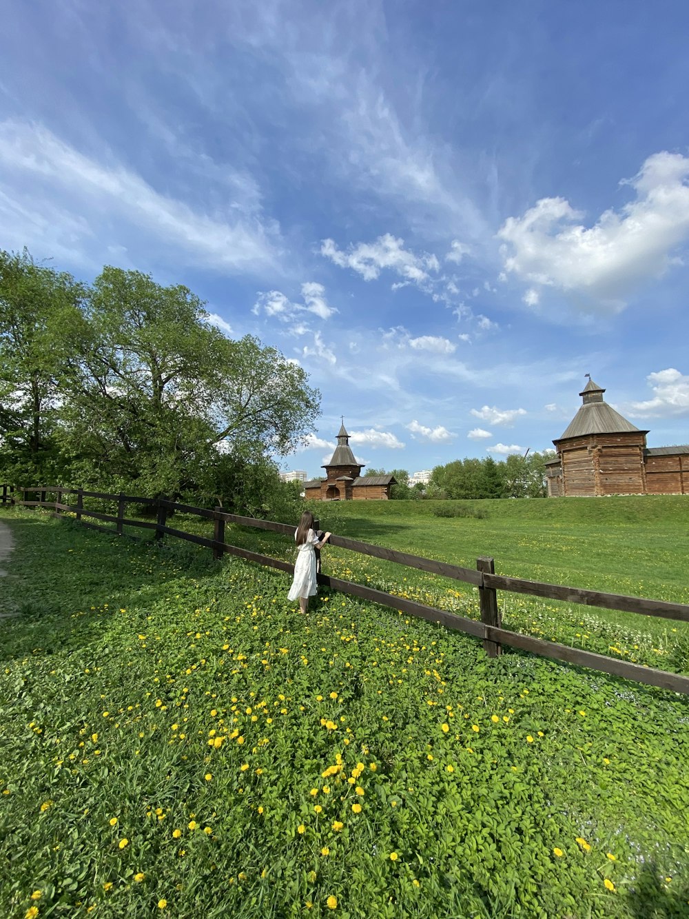 man in white robe walking on green grass field near brown wooden fence during daytime