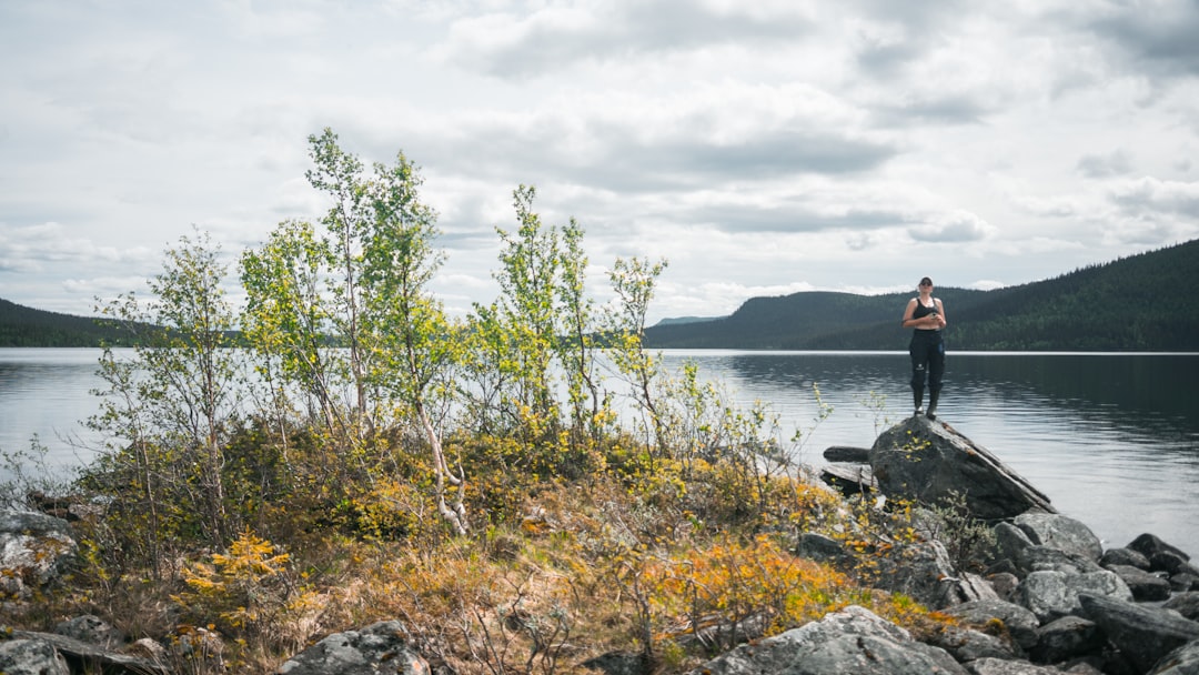 man in black jacket sitting on rock near body of water during daytime