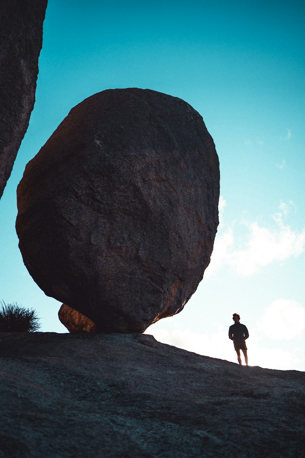 man in black shirt standing on gray rock during daytime