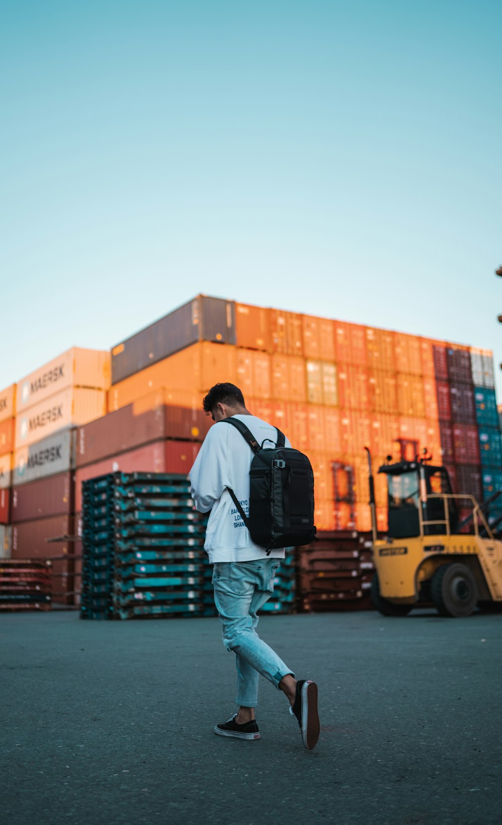 man in black jacket and blue denim jeans standing on yellow truck