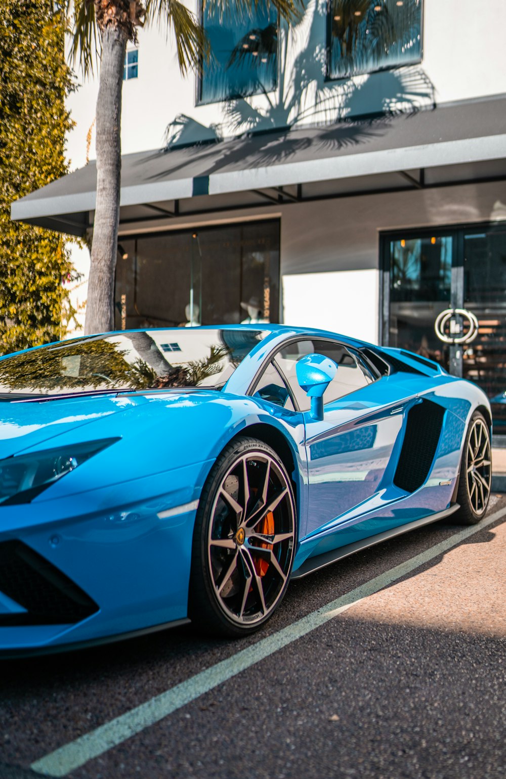 Blauer Lamborghini Aventador tagsüber in der Nähe des weißen Gebäudes geparkt