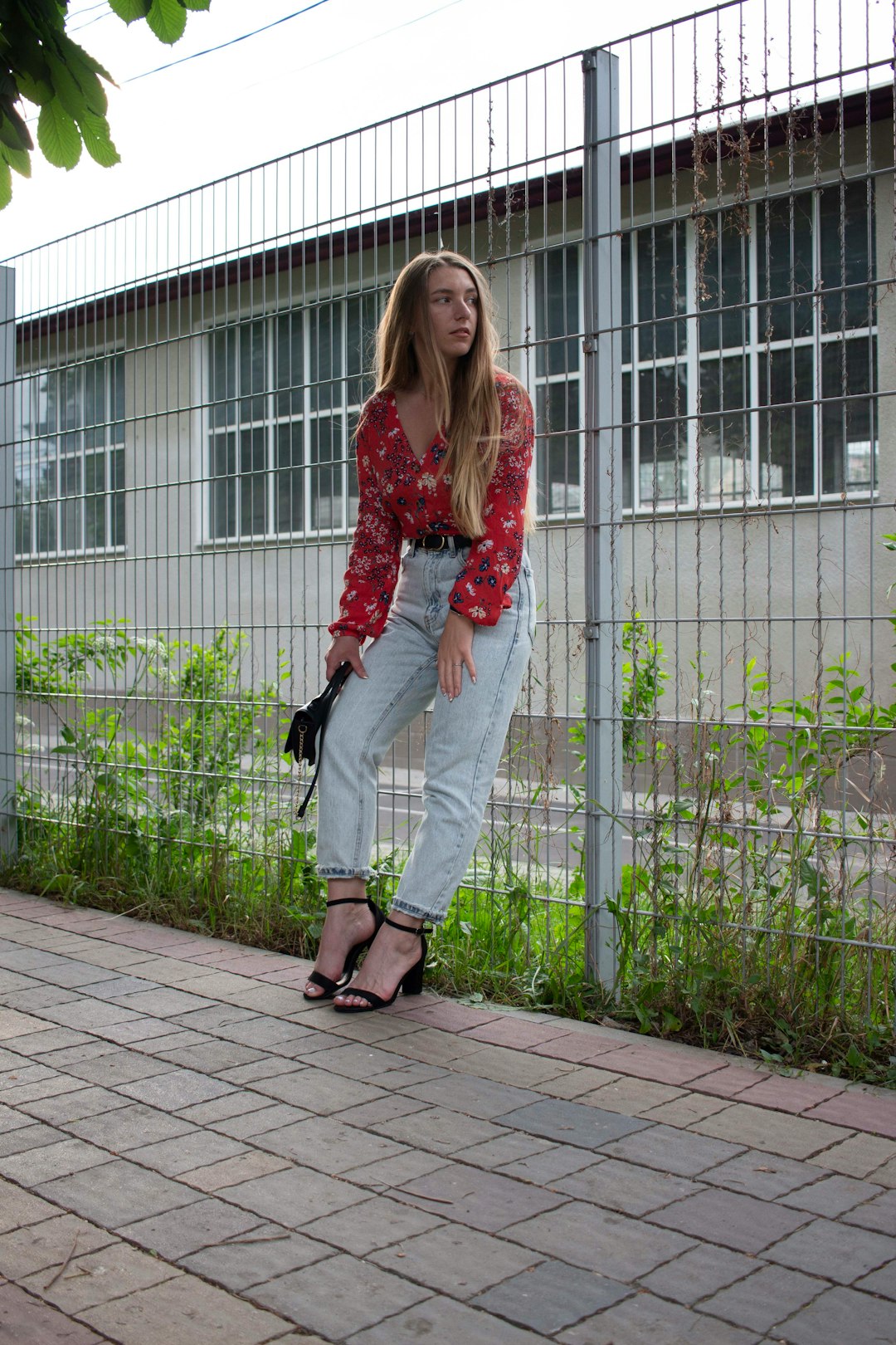 woman in red floral long sleeve shirt and white pants standing on gray concrete floor during