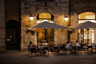 Cozy outdoor terrace of La Piazza with warm lighting and inviting tables in the evening.