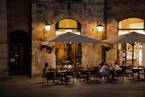 A cozy outdoor café terrace with people enjoying drinks and chatting in the evening.