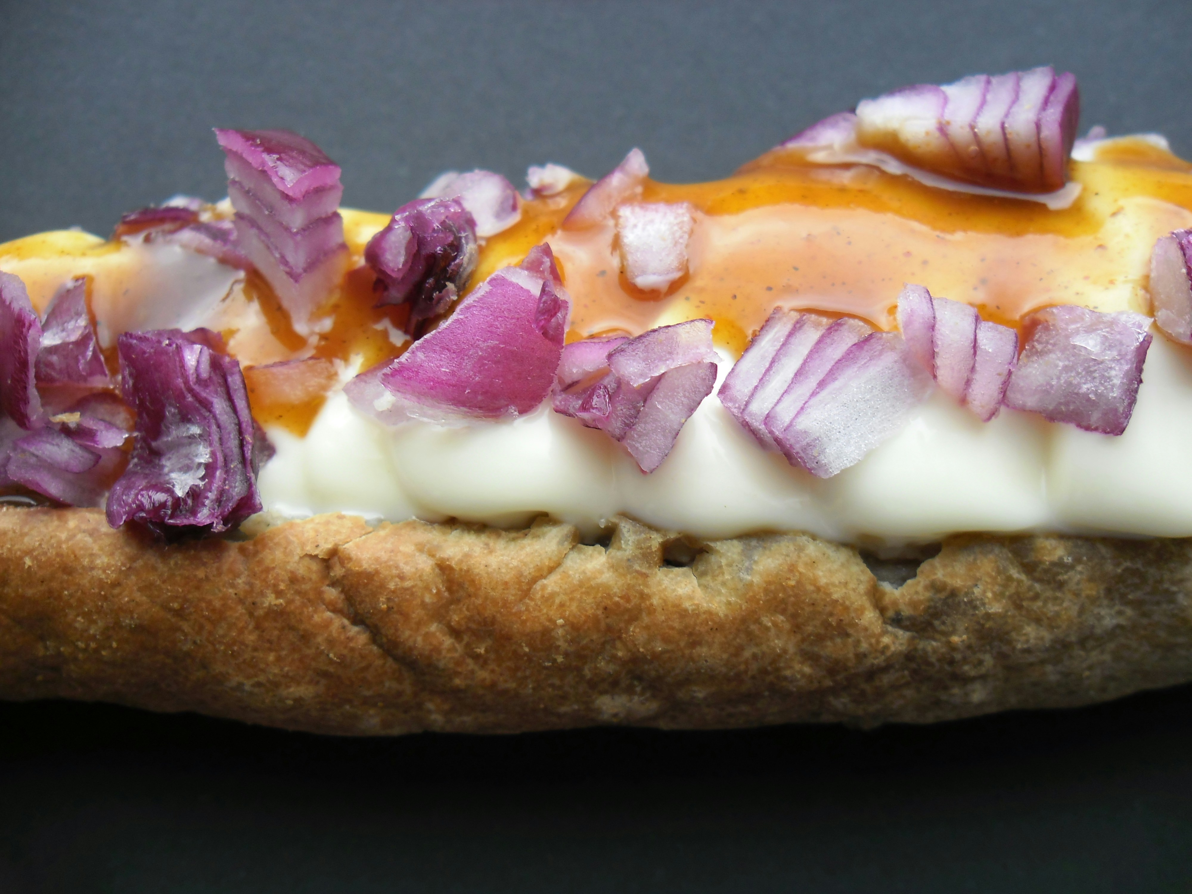 Perro caliente con papas ralladas y salsas coloridas