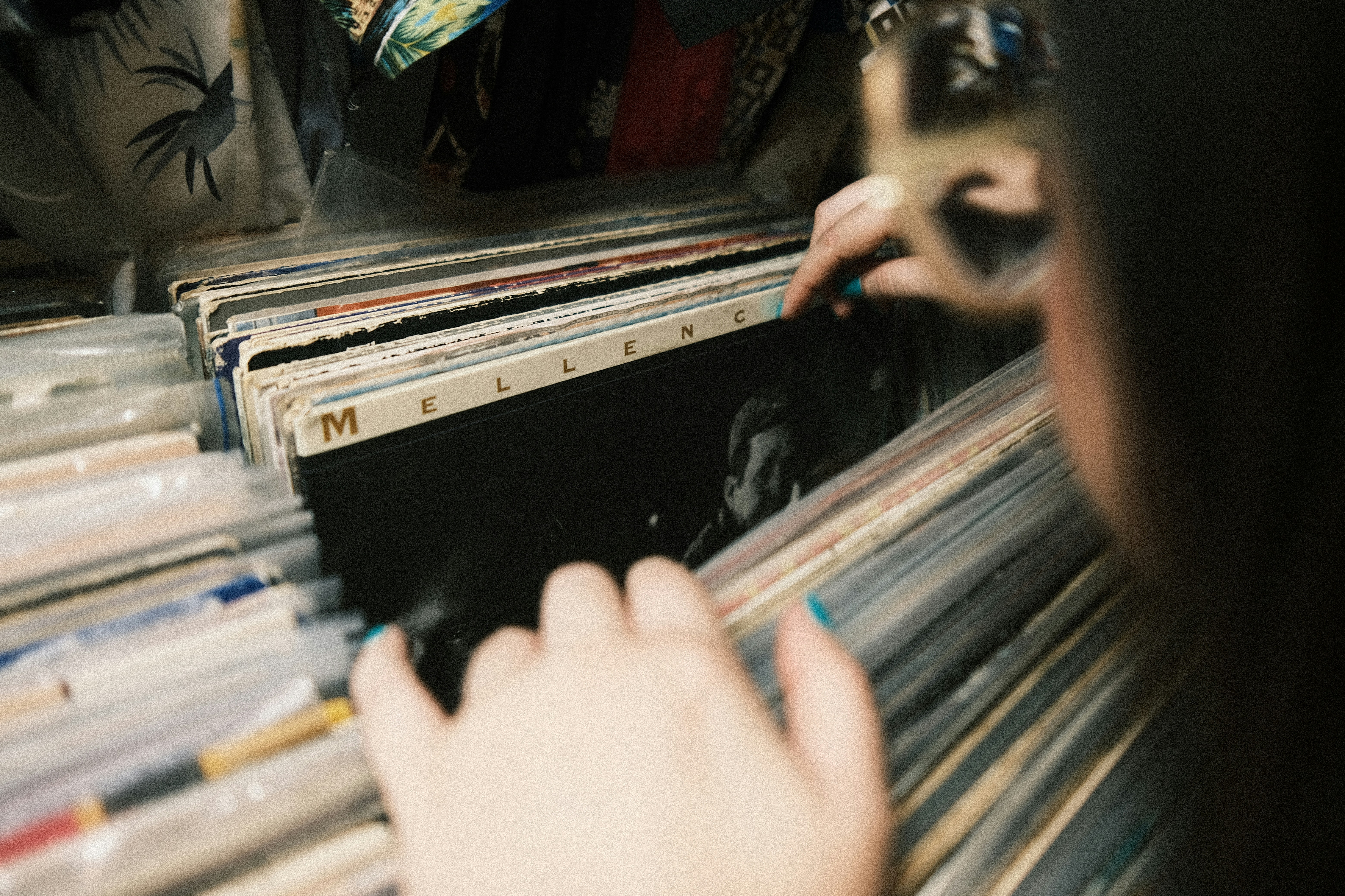 person holding black and white audio mixer, Woman flicking through vintage records in a thrift store.