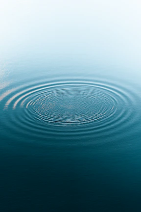 Ripples spreading across a calm ocean surface under a soft blue sky, illustrating value movement.