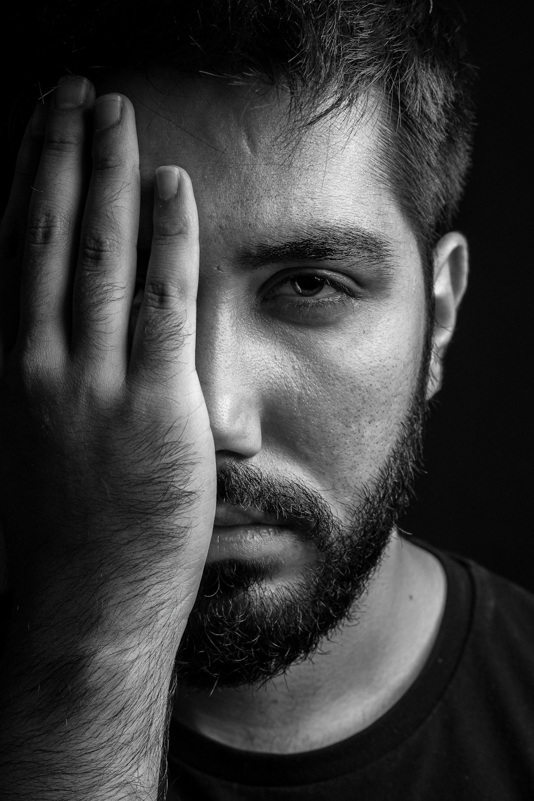 man in crew neck shirt covering his face