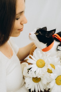woman in white tank top holding white and black cat