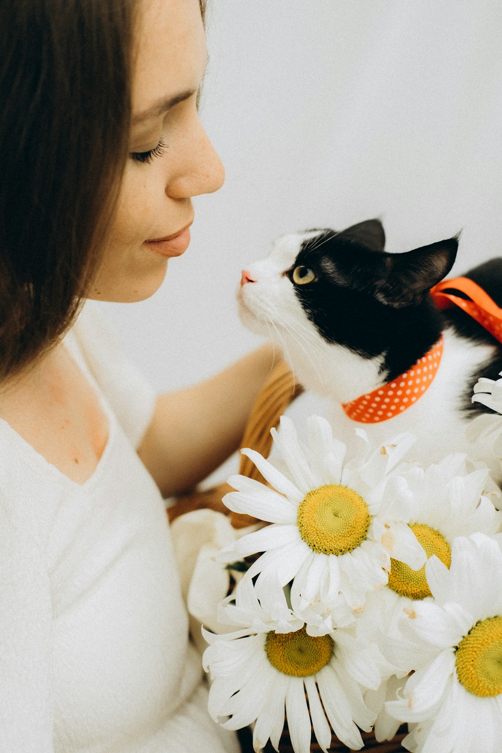woman in white tank top holding white and black cat