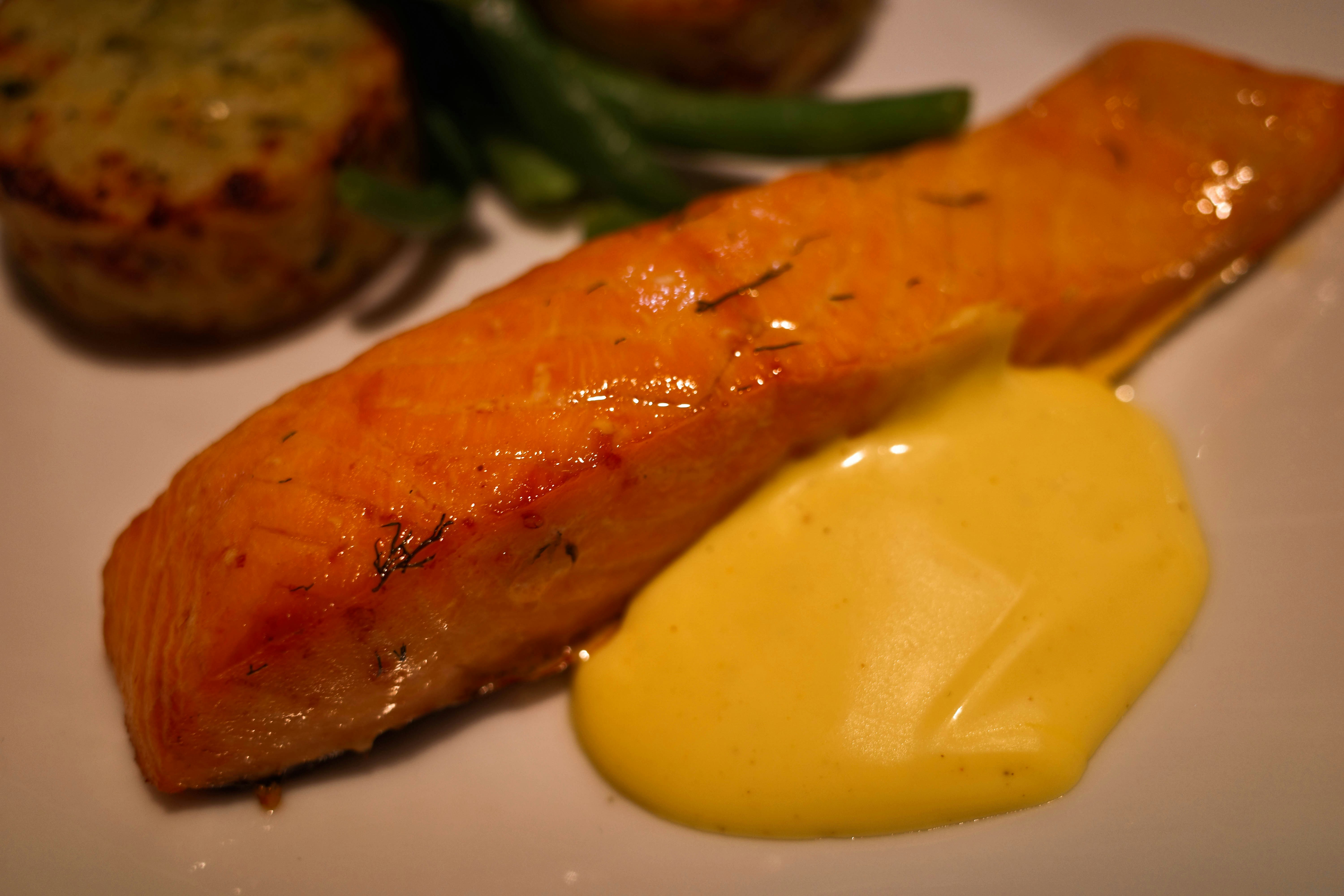 A beautiful sheet pan with a perfectly cooked salmon fillet, roasted asparagus, and golden-brown potato wedges, garnished with lemon slices and fresh herbs