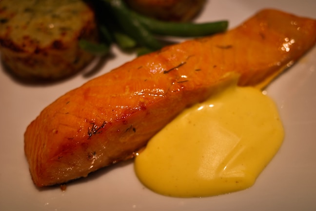 A close-up of perfectly cooked salmon with a side of asparagus and lemon wedges