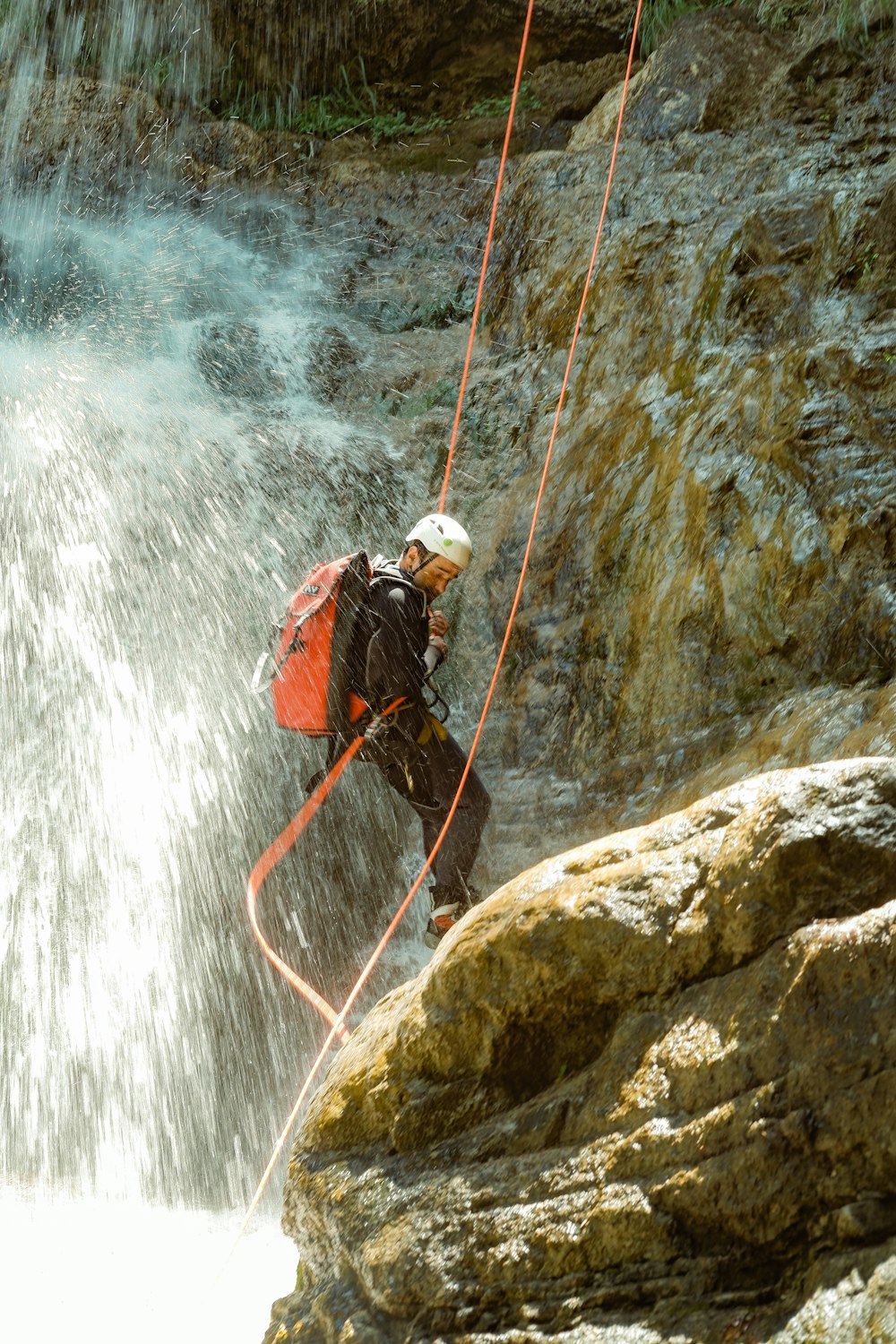 a man on a rope in front of a waterfall