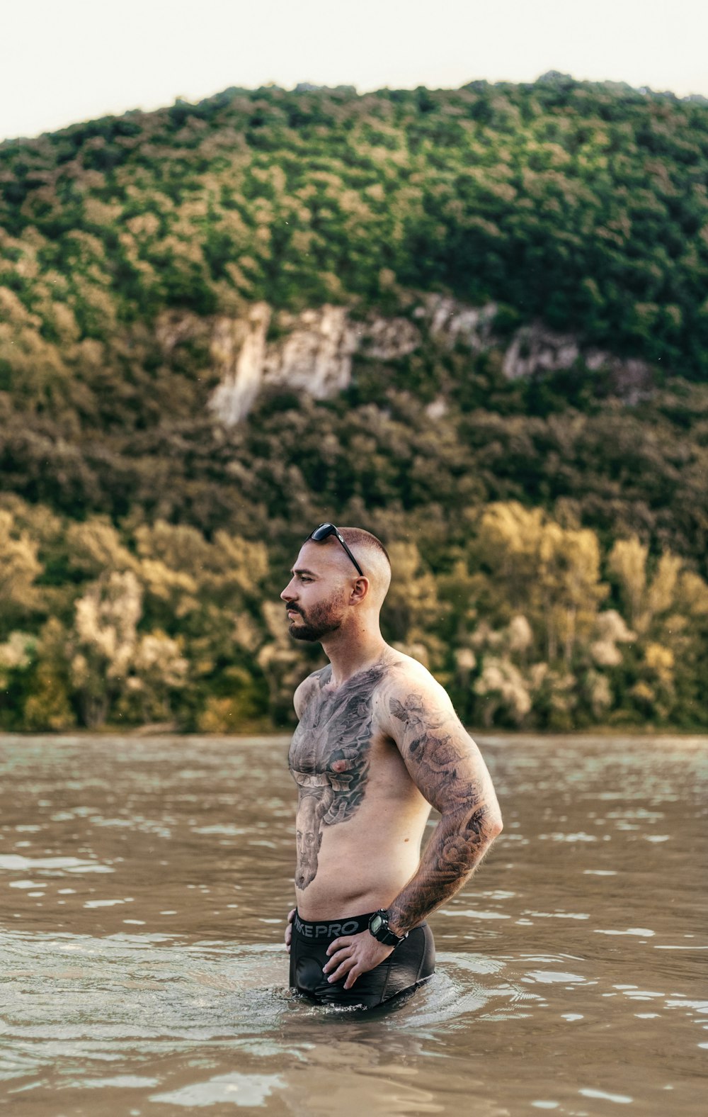 topless man in black frame eyeglasses standing on water during daytime