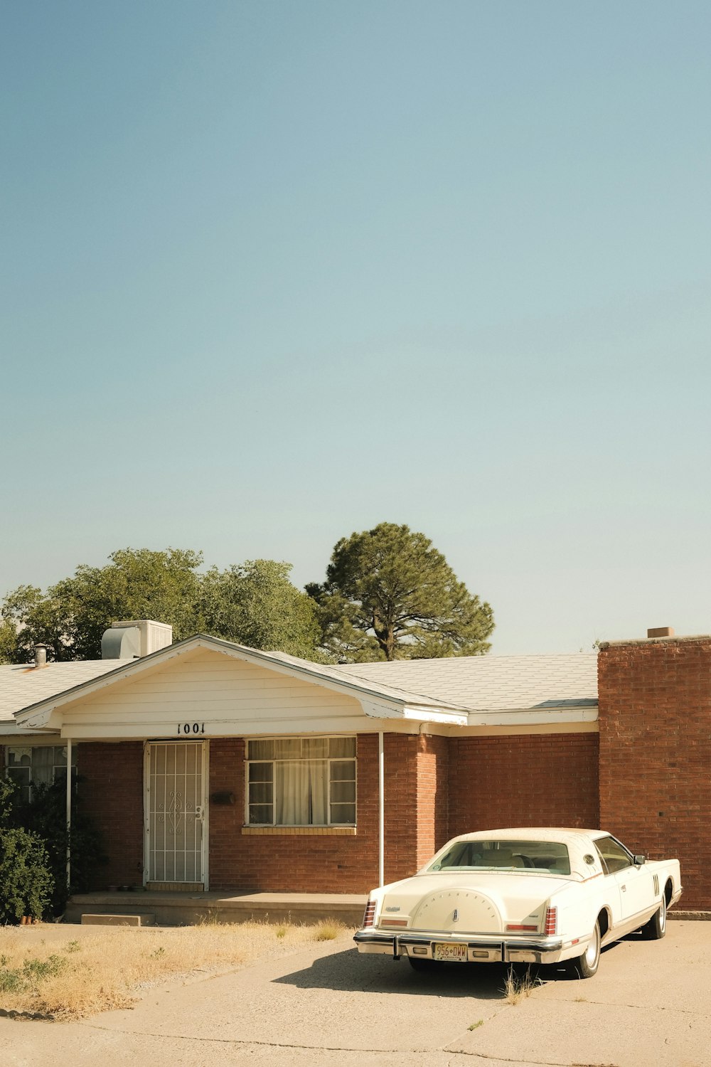 white car parked beside brown concrete house during daytime