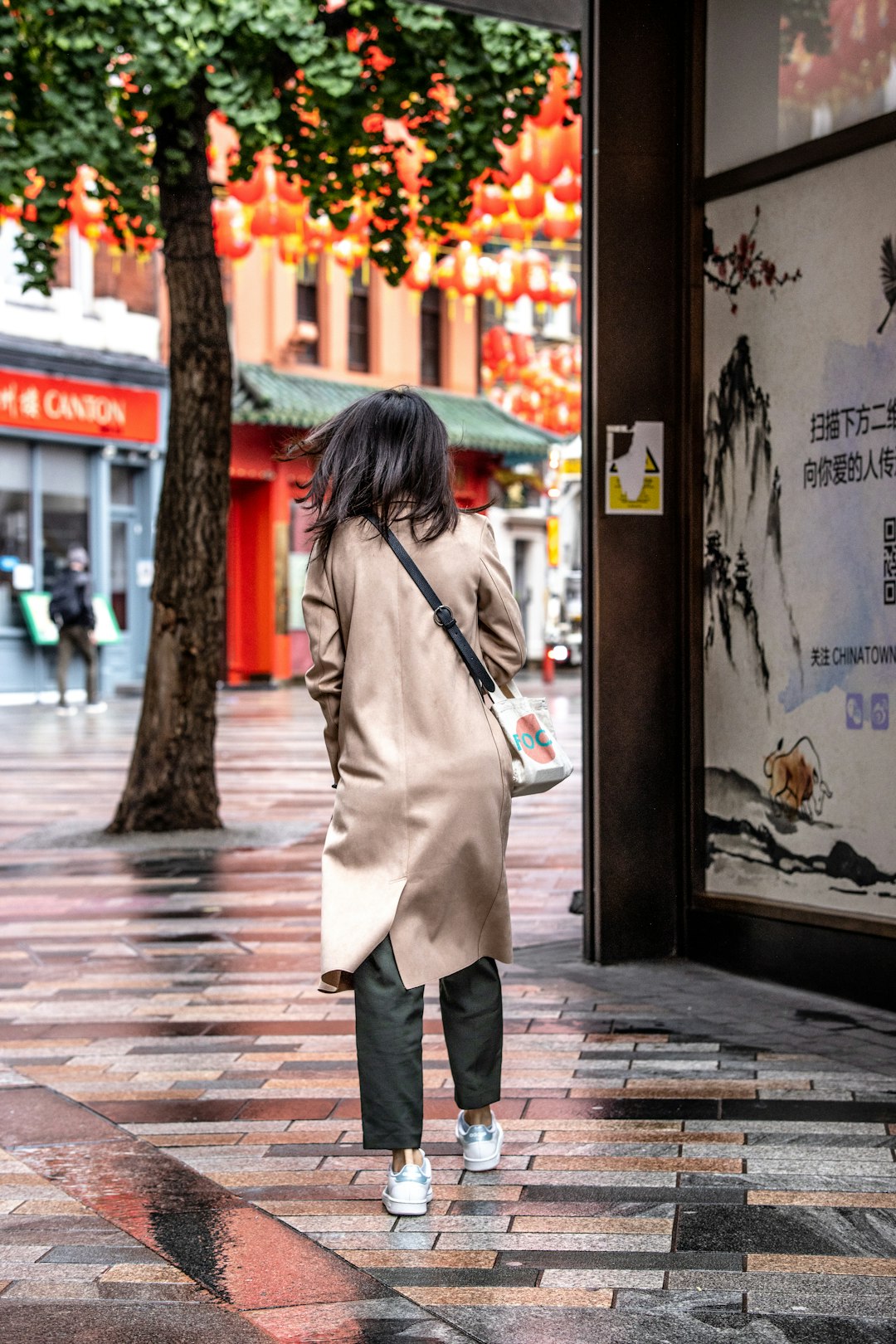 woman in white coat and black pants standing beside store during daytime