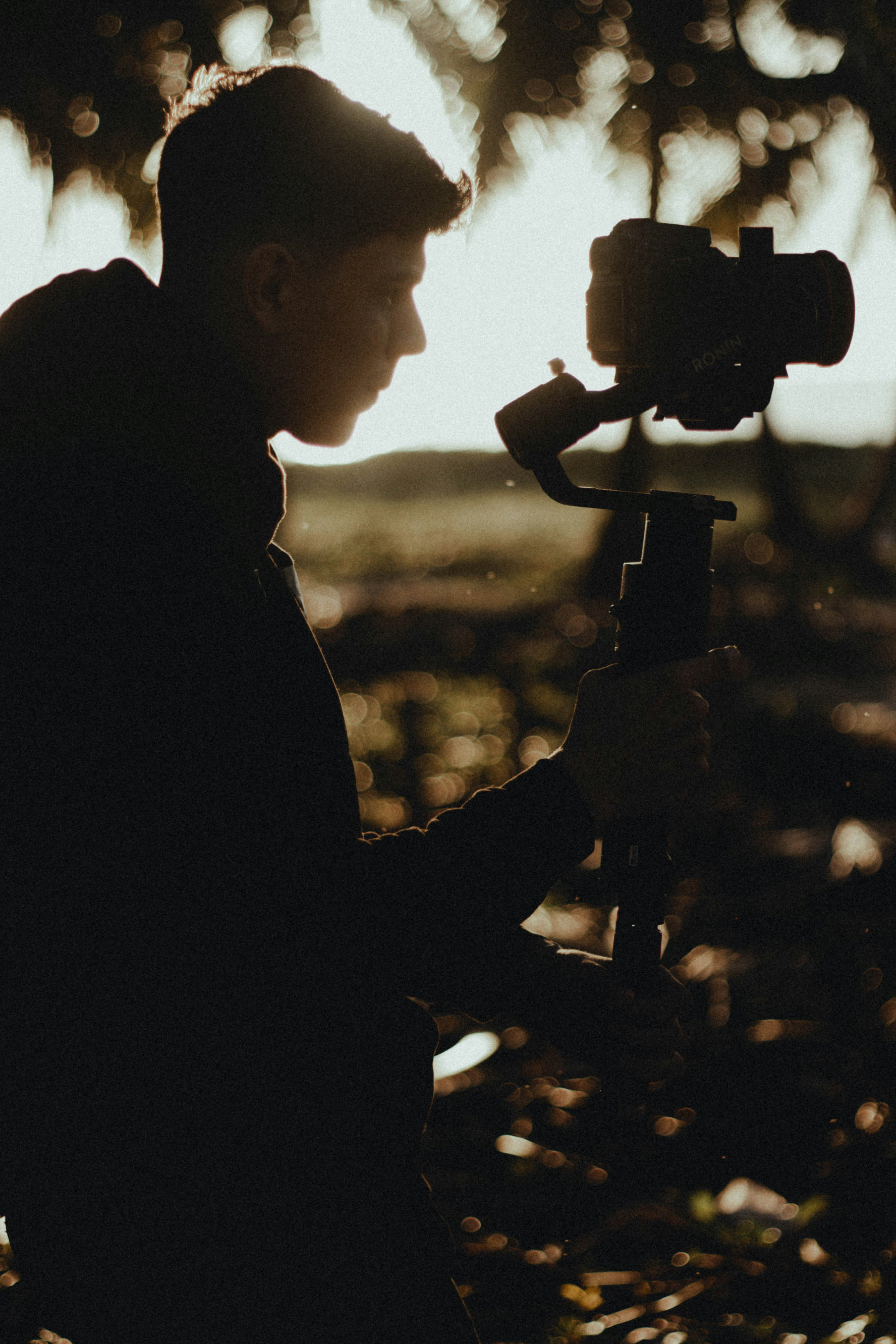 Wide shot of a videographer holding a camera on a gimbal outdoors.
