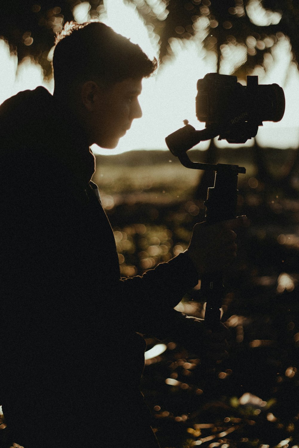 silhouette of man holding camera during sunset