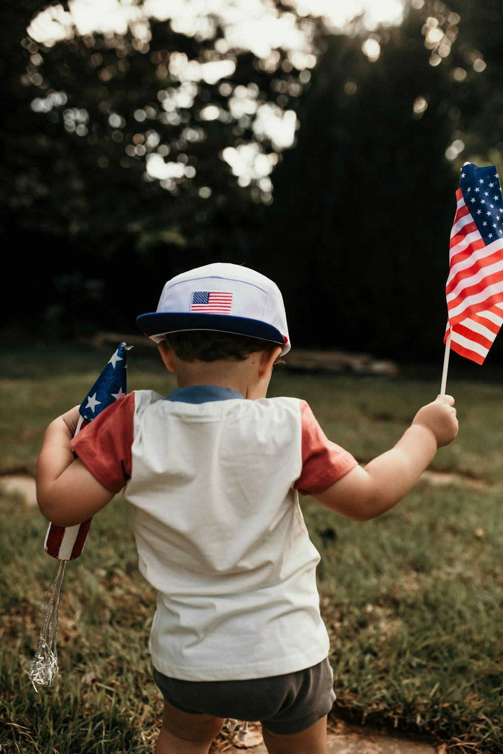 child in white crew neck t-shirt holding us a flag