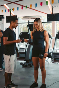 A personal trainer guiding a client through a workout in a bright Brooklyn gym.