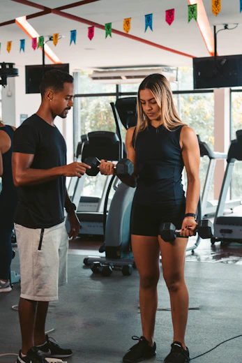 A friendly personal trainer guiding a young woman through a beginner workout routine in a cozy home gym.