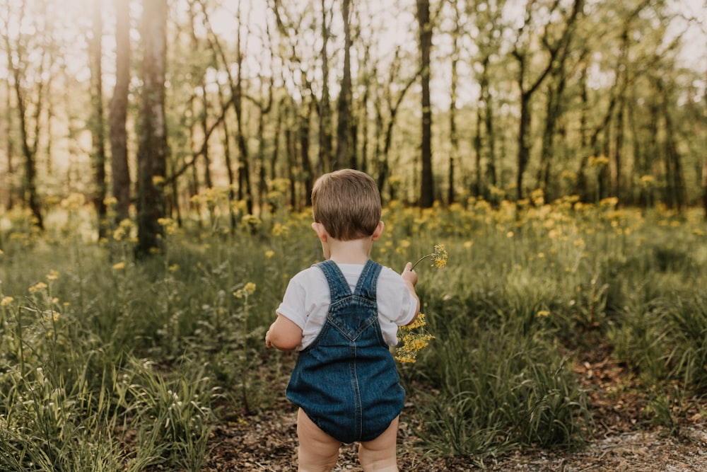 girl in blue denim shorts standing on green grass field during daytime