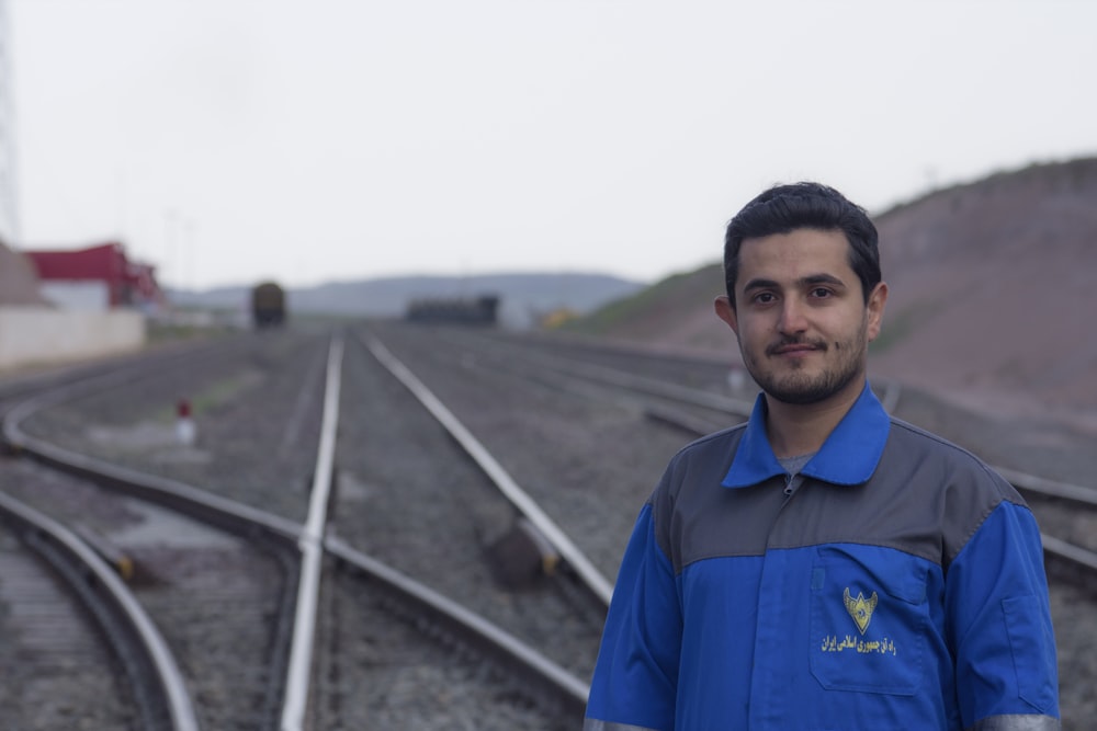 man in blue polo shirt standing on the road during daytime