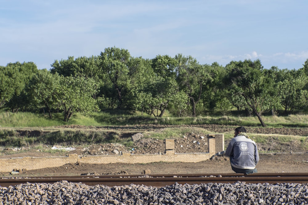 man in gray jacket sitting on brown wooden bench during daytime