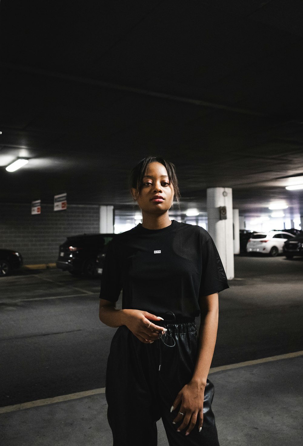 Donna in t-shirt girocollo nera in piedi sul parcheggio