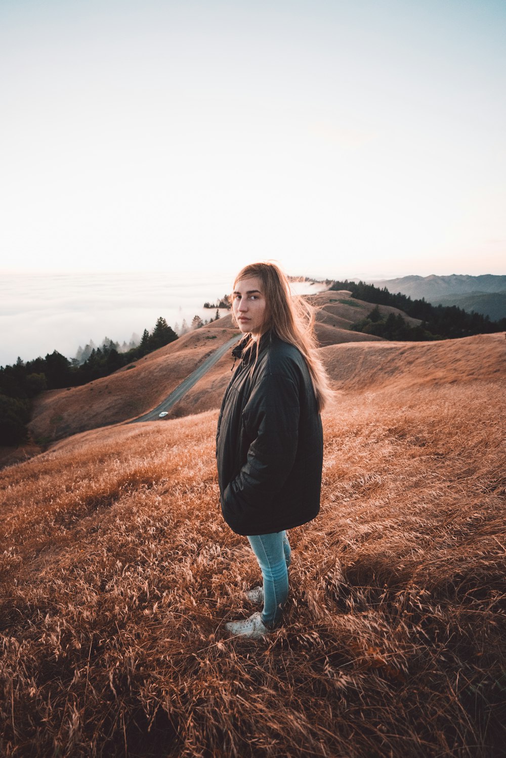 woman in black jacket standing on brown grass field during daytime