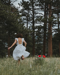 woman in white dress sitting on green grass field during daytime