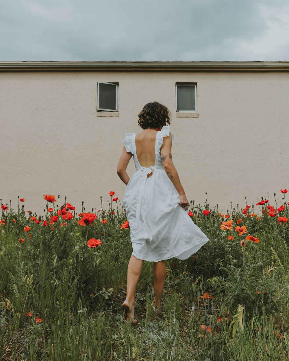 赤い花の前に立つ白いドレスの女性