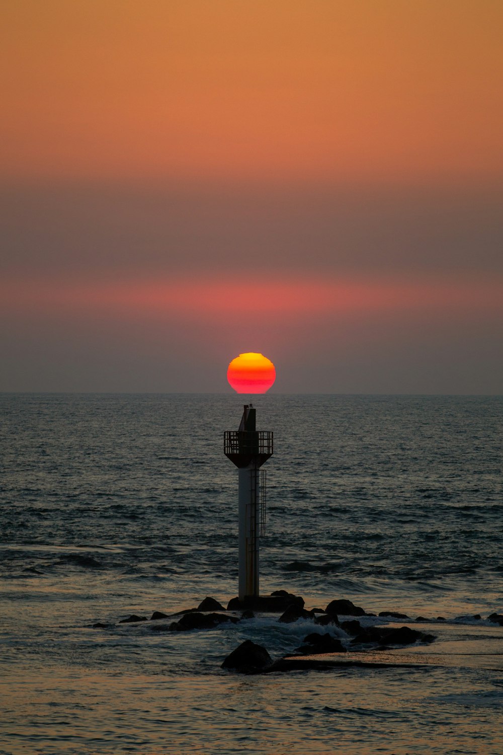 black and white lamp post near body of water during sunset