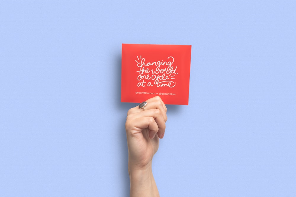 person holding red and white card