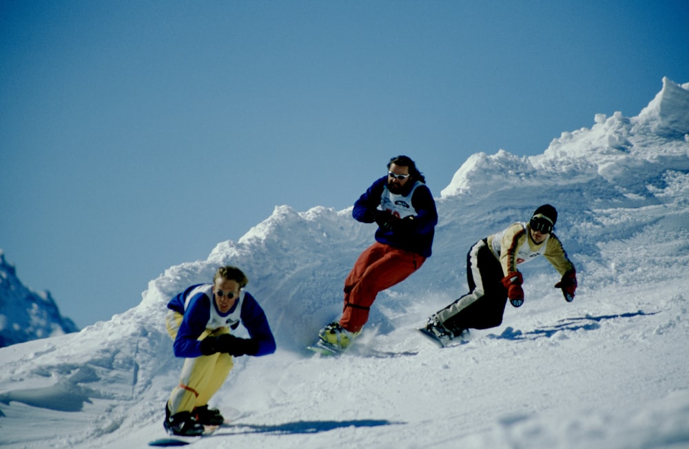 2 person in red and white snow suit riding on snow board during daytime