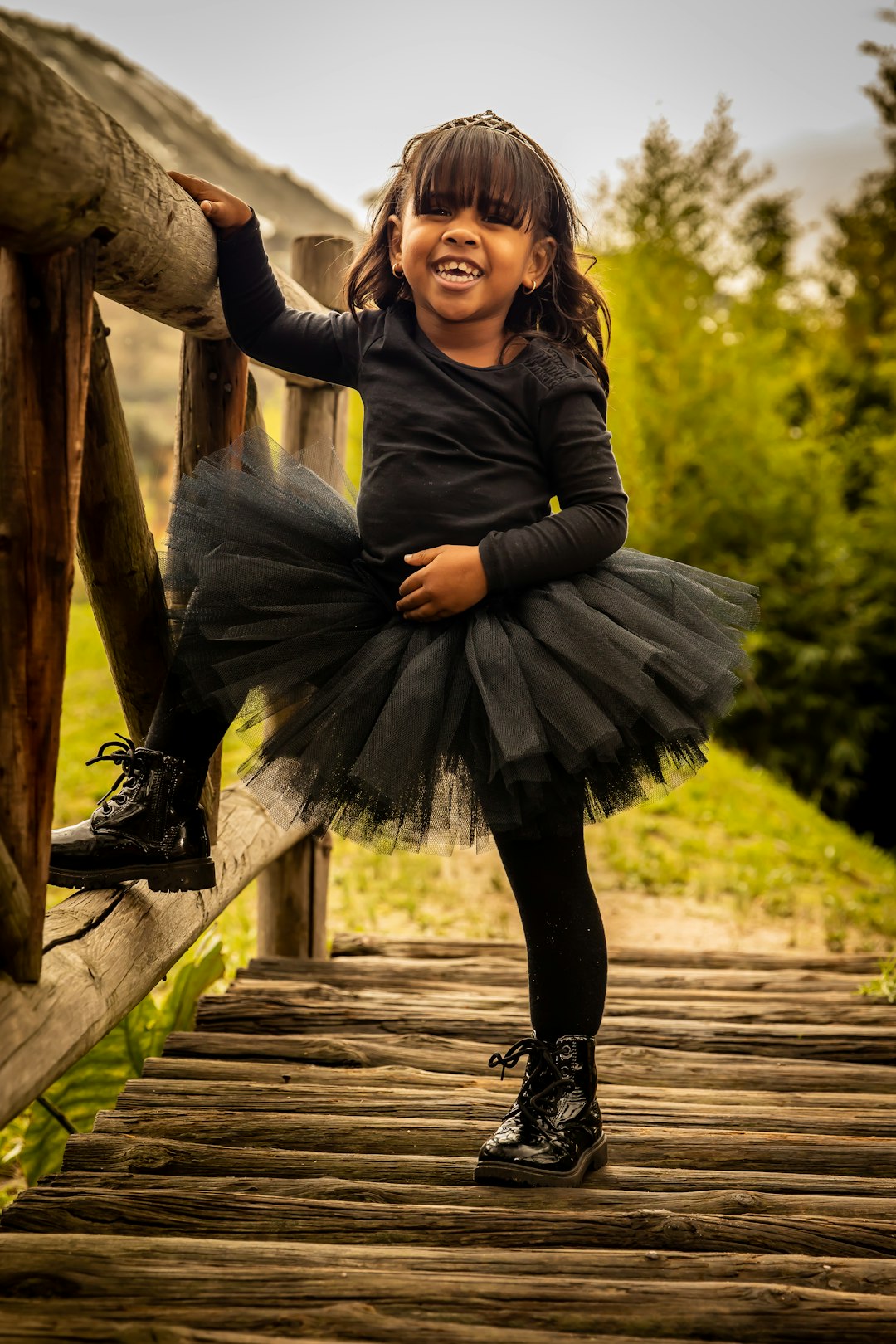 woman in black long sleeve dress sitting on brown wooden bridge during daytime