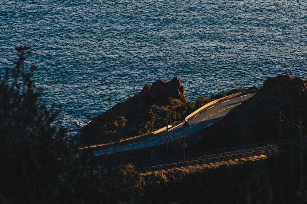 black car on road near body of water during daytime