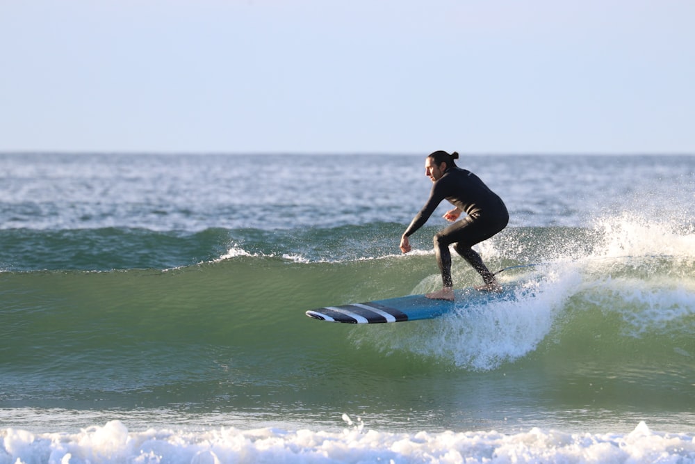 Mann im schwarzen Neoprenanzug Surfen auf Meereswellen tagsüber