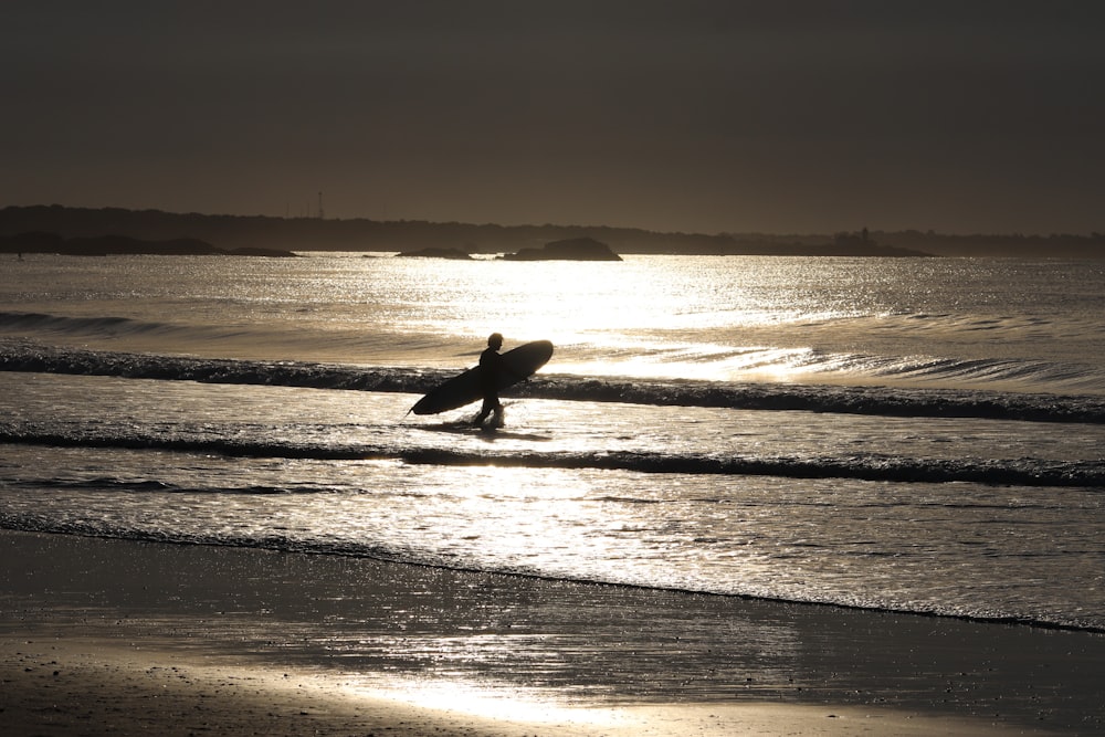 silhouette of man surfing on sea during sunset