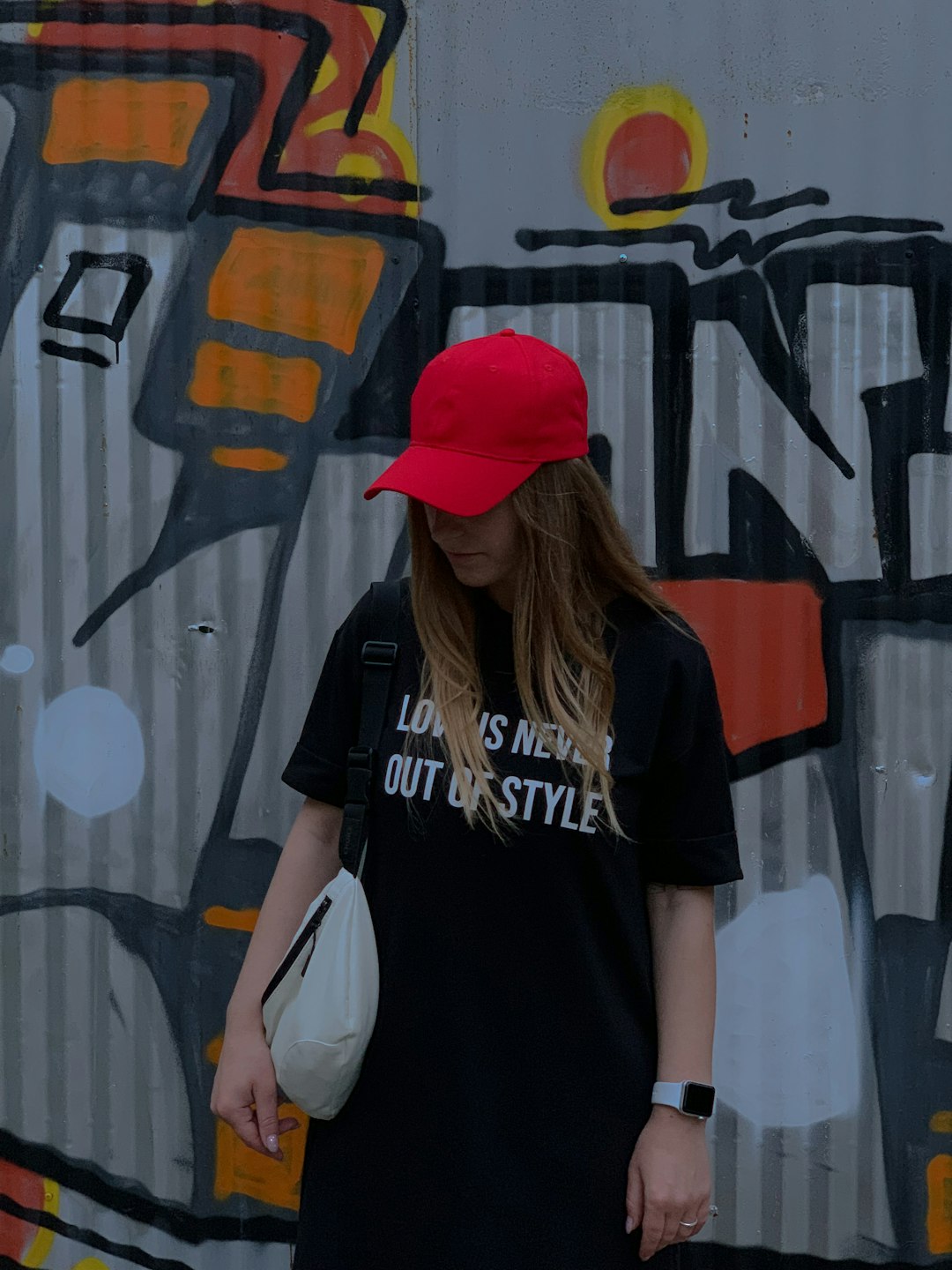 woman in black and white crew neck t-shirt wearing red cap standing beside wall with with with with with