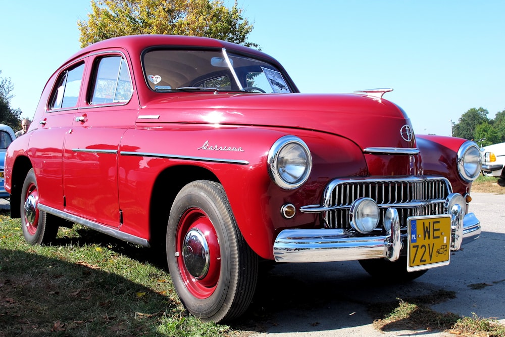 voiture de collection rouge sur le champ d’herbe verte pendant la journée