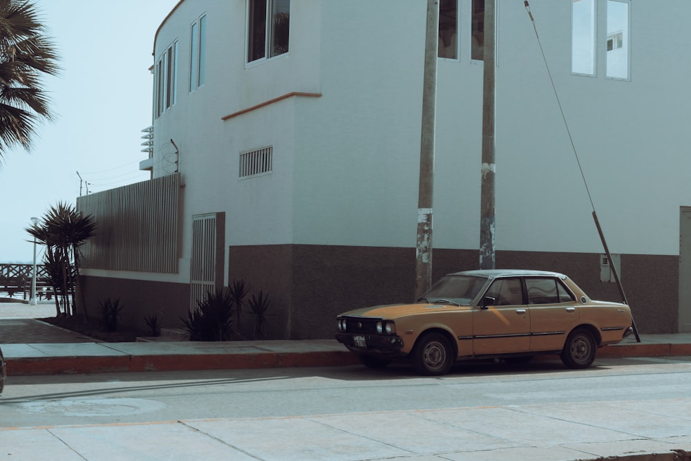yellow sedan parked beside beige concrete building during daytime
