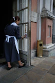 A friendly cleaner arriving at a bright, tidy home entrance.