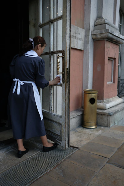 A friendly cleaner arriving at a bright, tidy home entrance.