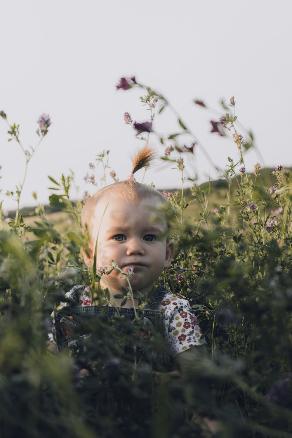 girl in white and black floral long sleeve shirt on green grass field during daytime