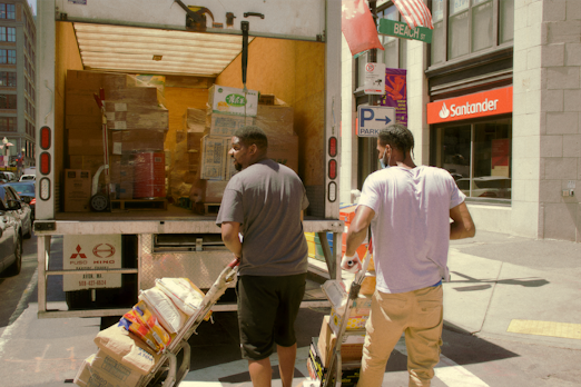 man in gray t-shirt and brown pants standing in front of white and red store