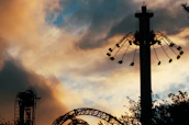 Dark carnival rides silhouetted against a blood-red moon with creepy shadows.