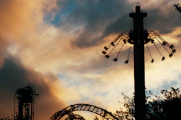 Dark carnival rides silhouetted against a blood-red moon with creepy shadows.
