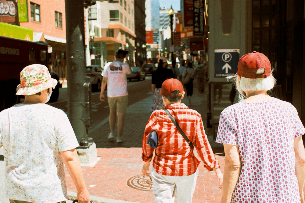 man in white and red plaid button up t-shirt standing on sidewalk during daytime