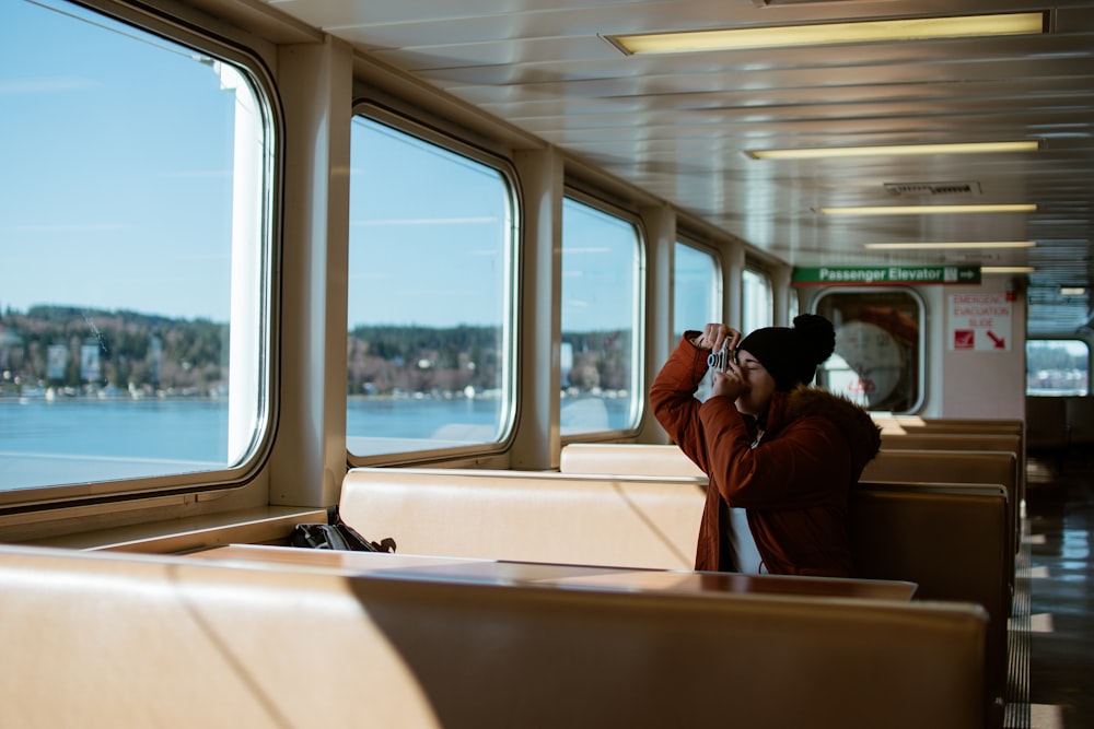 man in red jacket sitting beside window